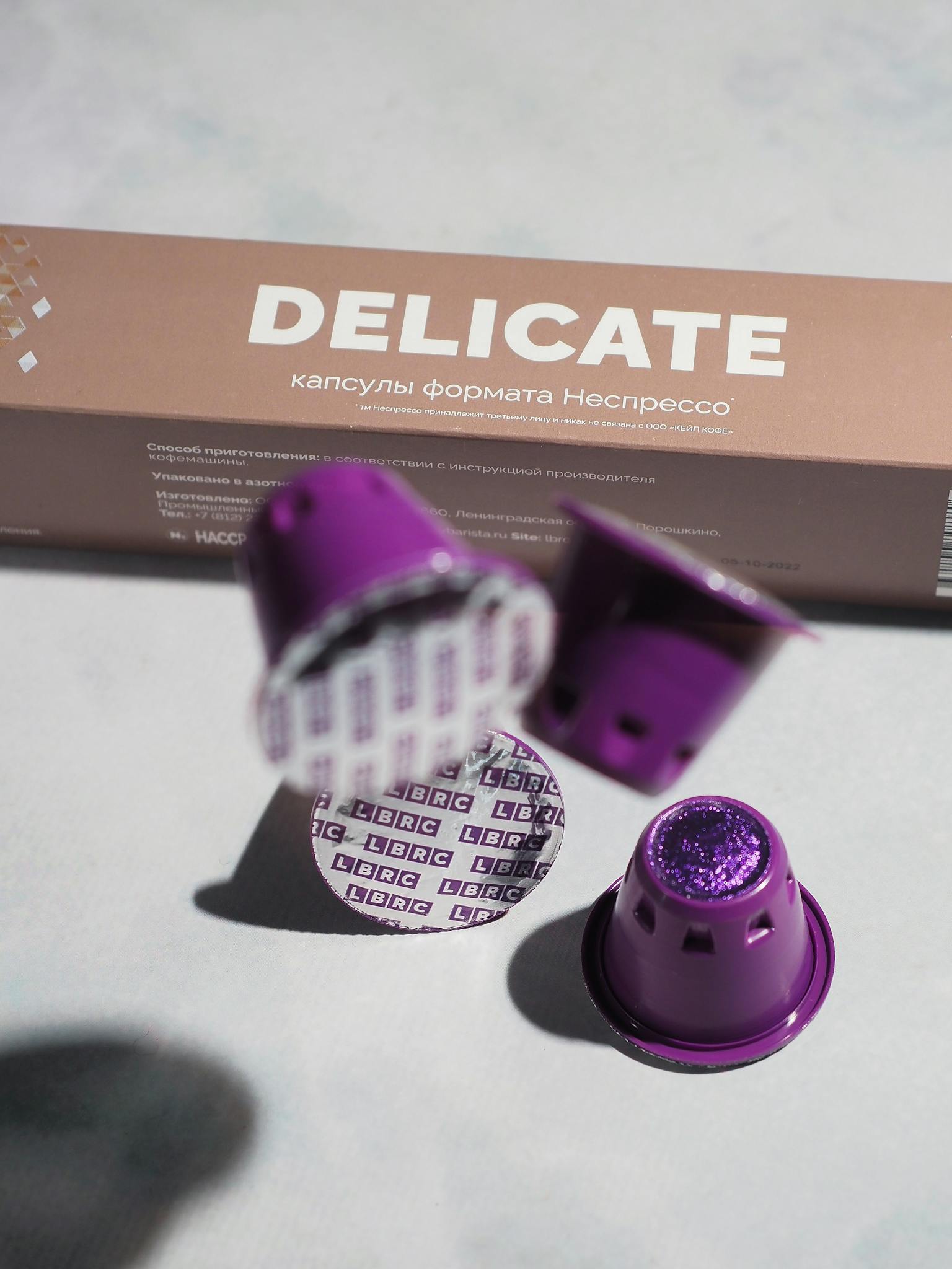 Close-up of purple coffee capsules next to packaging with Nespresso branding.